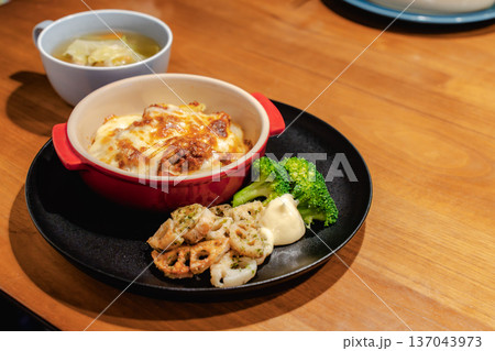 黒い皿に盛り付けたグラタンの夕食セットと野菜スープのある食卓 黒い皿に盛り付けたグラタンの夕食セットと野菜スープのある食卓 137043973