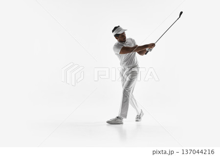 Golfer mid follow through stepping forward after drive on white background. Golfer mid follow through stepping forward after drive on white background. 137044216