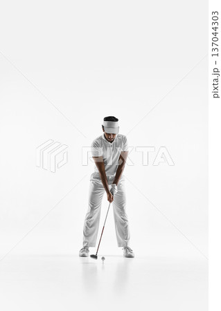 Golfer addressing ball before shot on white studio background 137044303