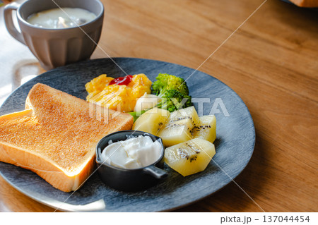 木のテーブルの朝食ワンプレート トーストとキウイとスクランブルエッグとブロッコリー 137044454
