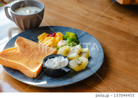 木のテーブルに朝食を用意したトーストと卵料理とフルーツのワンプレートとスープ 137044455
