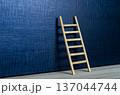 Wooden ladder leaning on deep blue cover with customizable space for text or ideas 137044744
