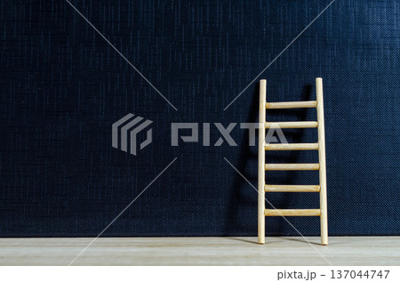 Wooden ladder standing on dark surface with customizable space for text or ideas, illustrating goal setting and personal development concept 137044747