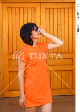 A woman in a bright dress looks at the sun through glasses A woman in a bright dress looks at the sun through glasses 137044945