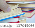 Hand flipping through colorful stacked books with customizable space for text or ideas, symbolizing knowledge and learning concept. 137045066