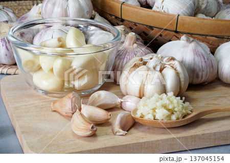 Close-up shot of minced garlic in wooden spoon placed on wooden chopping board In the kitchen prepared for food ingredients. Close-up shot of minced garlic in wooden spoon placed on wooden chopping board In the kitchen prepared for food ingredients. 137045154
