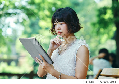 屋外でタブレットPCを使う若い女性 屋外でタブレットPCを使う若い女性 137047894