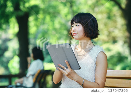 屋外でタブレットPCを使う若い女性 屋外でタブレットPCを使う若い女性 137047896