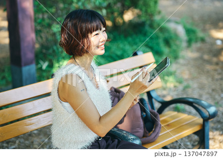 屋外でタブレットPCを使う若い女性 屋外でタブレットPCを使う若い女性 137047897