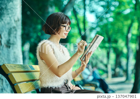 屋外でタブレットPCを使う若い女性 137047901