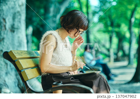 屋外でタブレットPCを使う若い女性 屋外でタブレットPCを使う若い女性 137047902