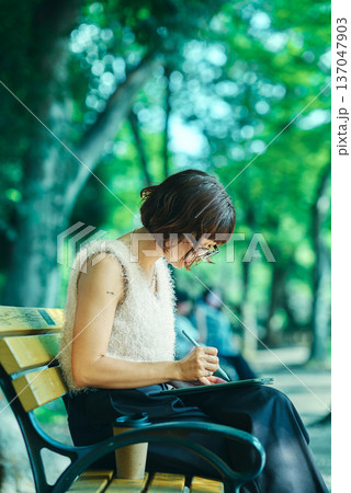 屋外でタブレットPCを使う若い女性 屋外でタブレットPCを使う若い女性 137047903