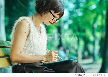 屋外でタブレットPCを使う若い女性 137047904