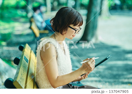 屋外でタブレットPCを使う若い女性 137047905