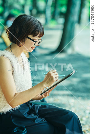 屋外でタブレットPCを使う若い女性 137047906