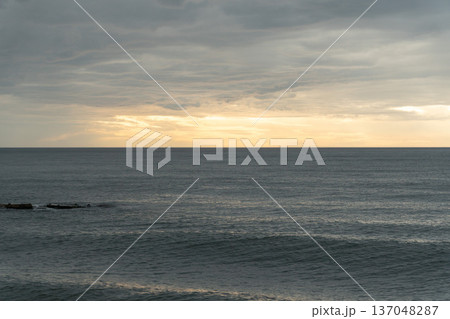 Calm Black Sea horizon under layered cloudy sky with soft golden light near sunset, wide seascape with muted blue gray tones and minimal composition. Tourism promotion, wellness branding, travel  137048287