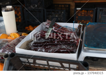 Traditional churchkhela sweets display on market stall with stacked grape walnut confections, oranges, knife, and scales in Abkhazia. Food marketing, culinary tourism, local product promotion Traditional churchkhela sweets display on market stall with stacked grape walnut confections, oranges, knife, and scales in Abkhazia. Food marketing, culinary tourism, local product promotion 137048315