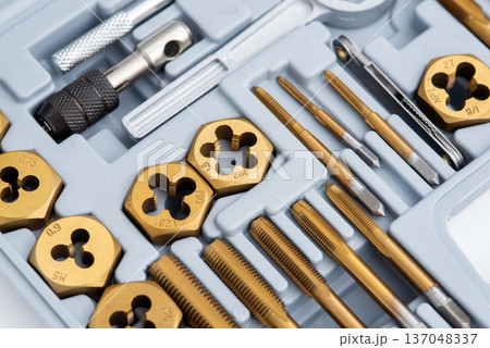 Close-up of a titanium-coated tap and die set for threading in a plastic organizer case. Close-up of a titanium-coated tap and die set for threading in a plastic organizer case. 137048337