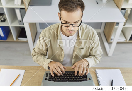 Focused writer editing page on vintage typewriter at modern home office workspace 137048452