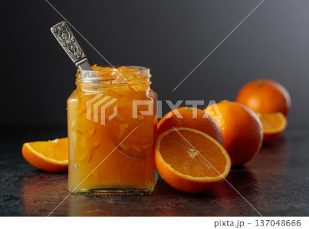 Homemade orange jam in a glass jar on a black table. 137048666