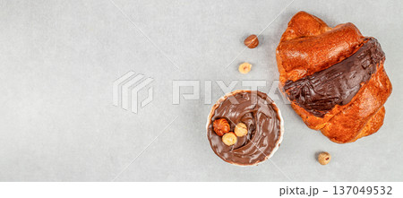 Chocolate croissant with hazelnut spread and nuts, top view on light background Chocolate croissant with hazelnut spread and nuts, top view on light background 137049532