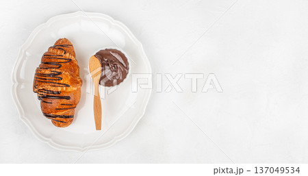 Chocolate drizzled croissant with spread on white plate top view 137049534