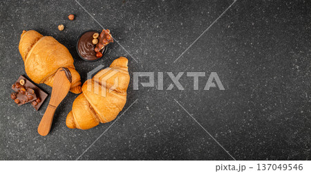 Croissants with chocolate spread and hazelnut pieces on dark background, top view with copy space Croissants with chocolate spread and hazelnut pieces on dark background, top view with copy space 137049546