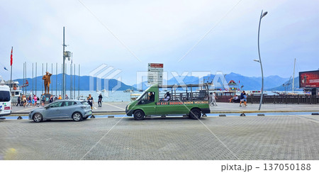 Green tourist bus parked near waterfront with scenic mountains in background Green tourist bus parked near waterfront with scenic mountains in background 137050188