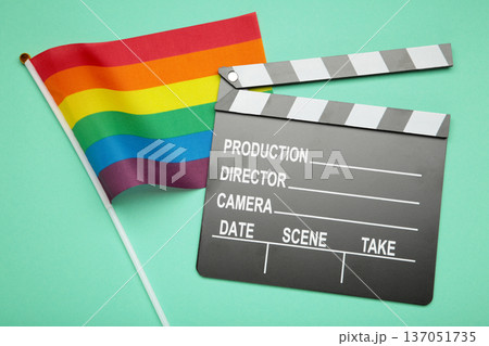 A rainbow flag and black clapperboard on mint background. Top view. A rainbow flag and black clapperboard on mint background. Top view. 137051735