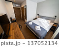 Modern minimalist hotel bedroom interior with double bed workspace and natural daylight 137052134