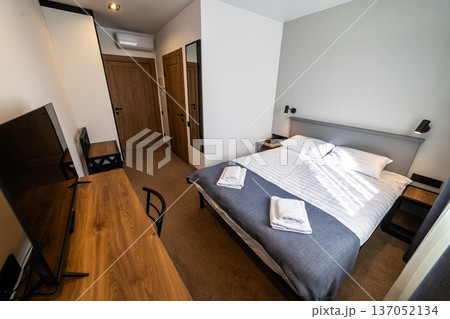 Modern minimalist hotel bedroom interior with double bed workspace and natural daylight 137052134