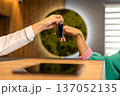 Receptionist giving hotel room key to guest during check in at modern reception desk 137052135