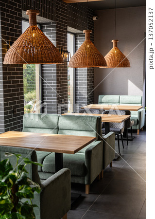Stylish modern restaurant interior with cozy seating and natural light from large windows 137052137