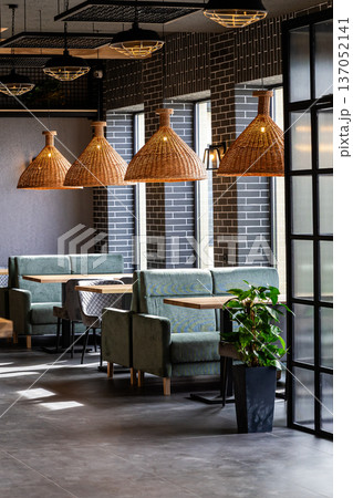 Stylish modern restaurant interior with cozy seating and natural light from large windows 137052141