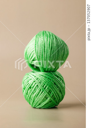 A ball of green recycled polyester synthetic fabric on beige background. Green living, plastic recycling, reuse A ball of green recycled polyester synthetic fabric on beige background. Green living, plastic recycling, reuse 137052907
