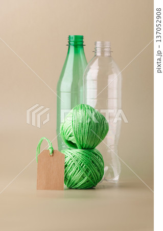 Empty plastic bottles, several skeins of polyester thread, blank label promoting recycling, sustainability, eco-friendly production. Green lifestyle, eco-technologies 137052908