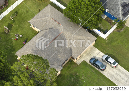 Aerial view of typical contemporary american private house with roof top covered with asphalt shingles and green lawn on yard 137052959