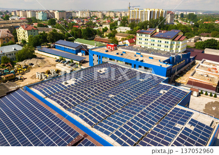 Aerial view of many photo voltaic solar panels mounted of industrial building roof. Aerial view of many photo voltaic solar panels mounted of industrial building roof. 137052960