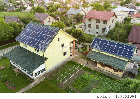 Aerial top view of new modern residential house cottage with blue shiny solar photo voltaic panels system on roof. Renewable ecological green energy production concept. 137052961