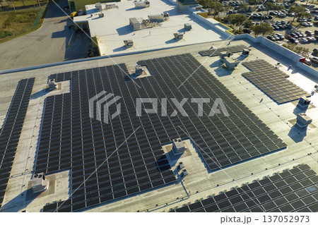 Aerial view of solar power plant with blue photovoltaic panels mounted on industrial building roof for producing green ecological electricity. Production of sustainable energy concept Aerial view of solar power plant with blue photovoltaic panels mounted on industrial building roof for producing green ecological electricity. Production of sustainable energy concept 137052973