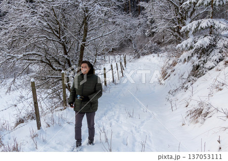 Woman walking in the snowy mountains looking at the camera 137053111