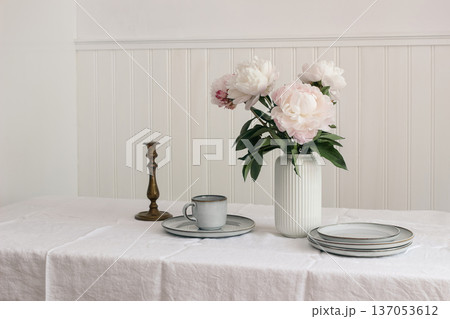 Minimal Dining Table Setting. Pink Peonies in Vase. Spring kitchen dinning room still life. Neutral Scandinavian Interior. Ceramic Plates, old candleholder. Cup of tea, Coffee. Elegant Home Decor. Minimal Dining Table Setting. Pink Peonies in Vase. Spring kitchen dinning room still life. Neutral Scandinavian Interior. Ceramic Plates, old candleholder. Cup of tea, Coffee. Elegant Home Decor. 137053612