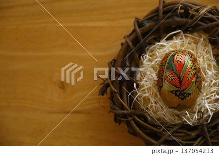 木製テーブルの上に置かれた鳥の巣の中の伝統的な麦わら細工のイースターエッグのコピースペースがある写真 137054213