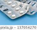 White pills in foil blister packs are placed on a blue background. 137054270