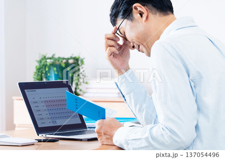 年金手帳を見ながら考える中高年男性 137054496