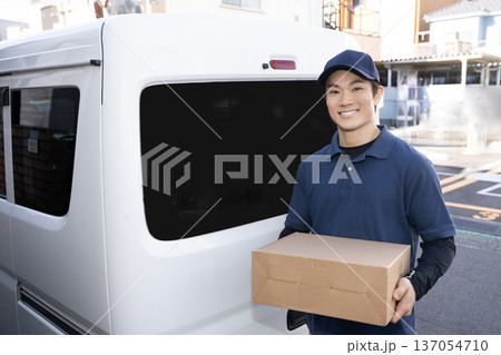 笑顔で荷物を届ける宅配便の男性 笑顔で荷物を届ける宅配便の男性 137054710