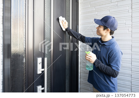 玄関の扉の清掃をするハウスクリーニングの男性 137054773