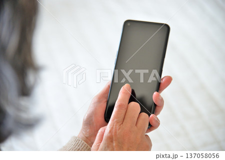 携帯電話を操作するシニア女性 137058056
