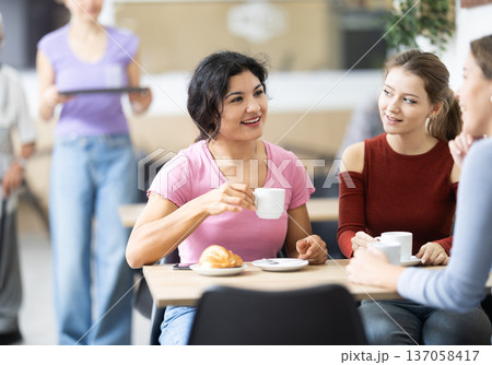 Three girlfriends drinking coffee and chatting Three girlfriends drinking coffee and chatting 137058417