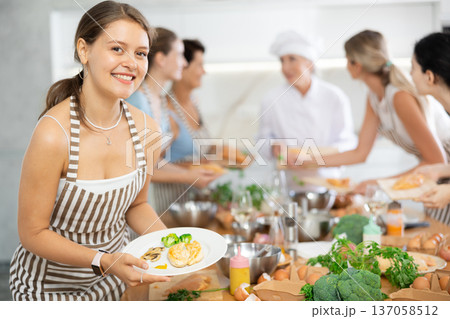Girl after class at culinary master class shows plate with delicious baked chicken fillet Girl after class at culinary master class shows plate with delicious baked chicken fillet 137058512